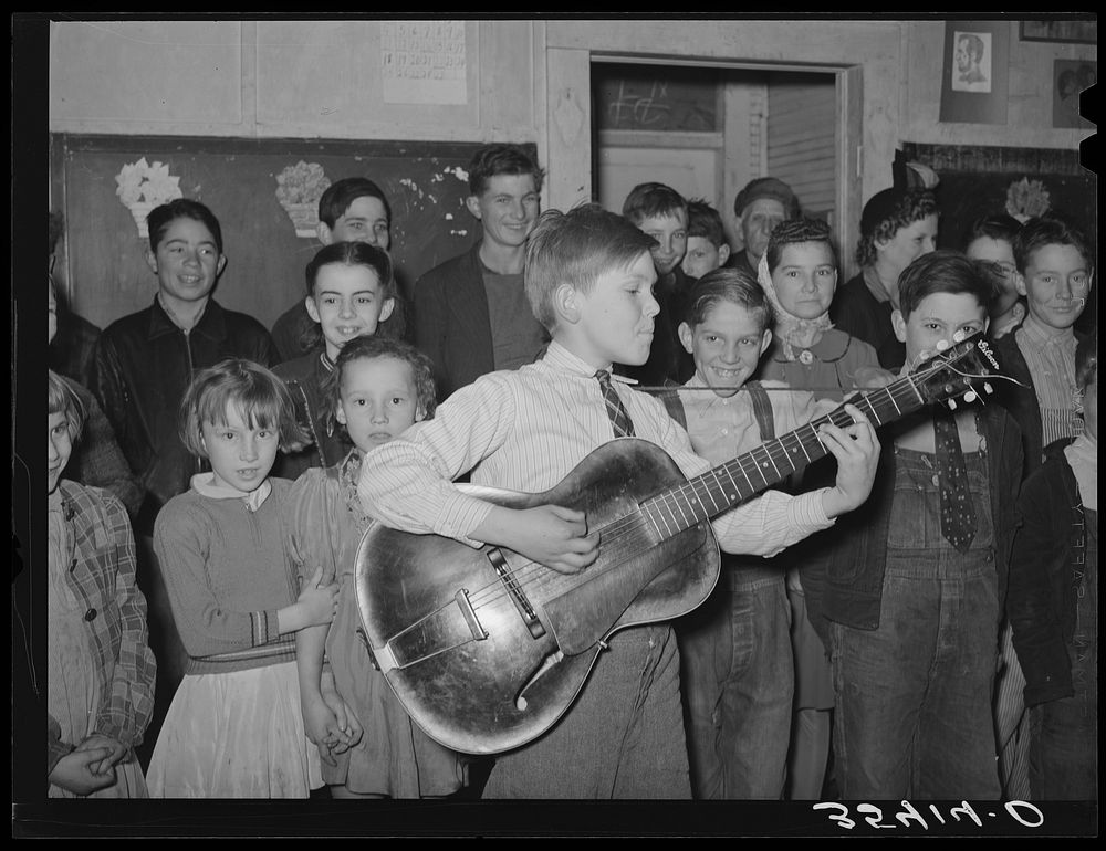 Boy playing and singing "Sipping cider through a straw" at pie supper in Muskogee County, Oklahoma. See general caption 24…
