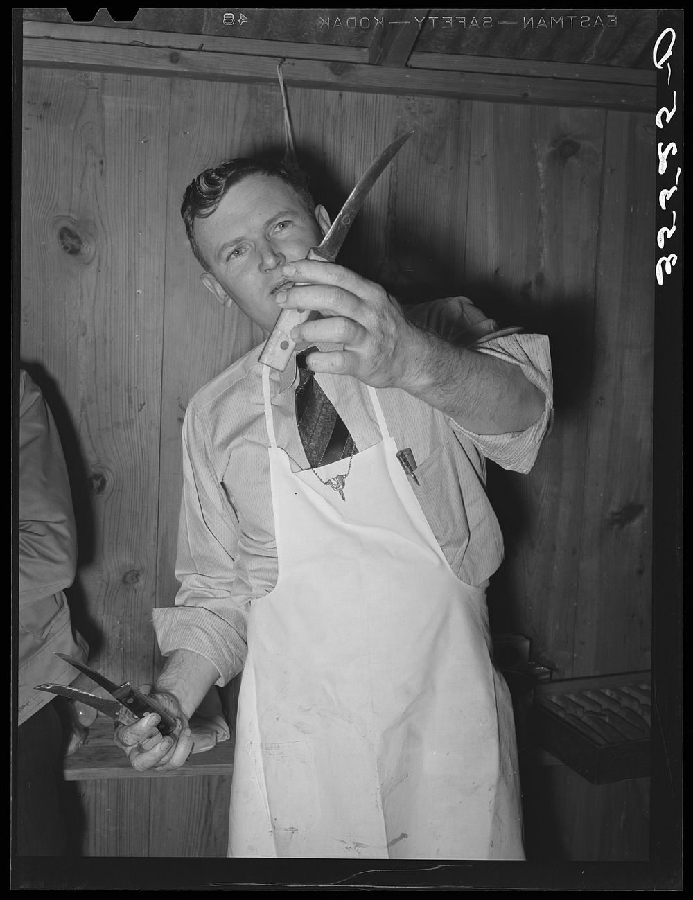 FSA (Farm Security Administration) supervisor exhibiting the type of knife used in his meat cutting demonstration before a…