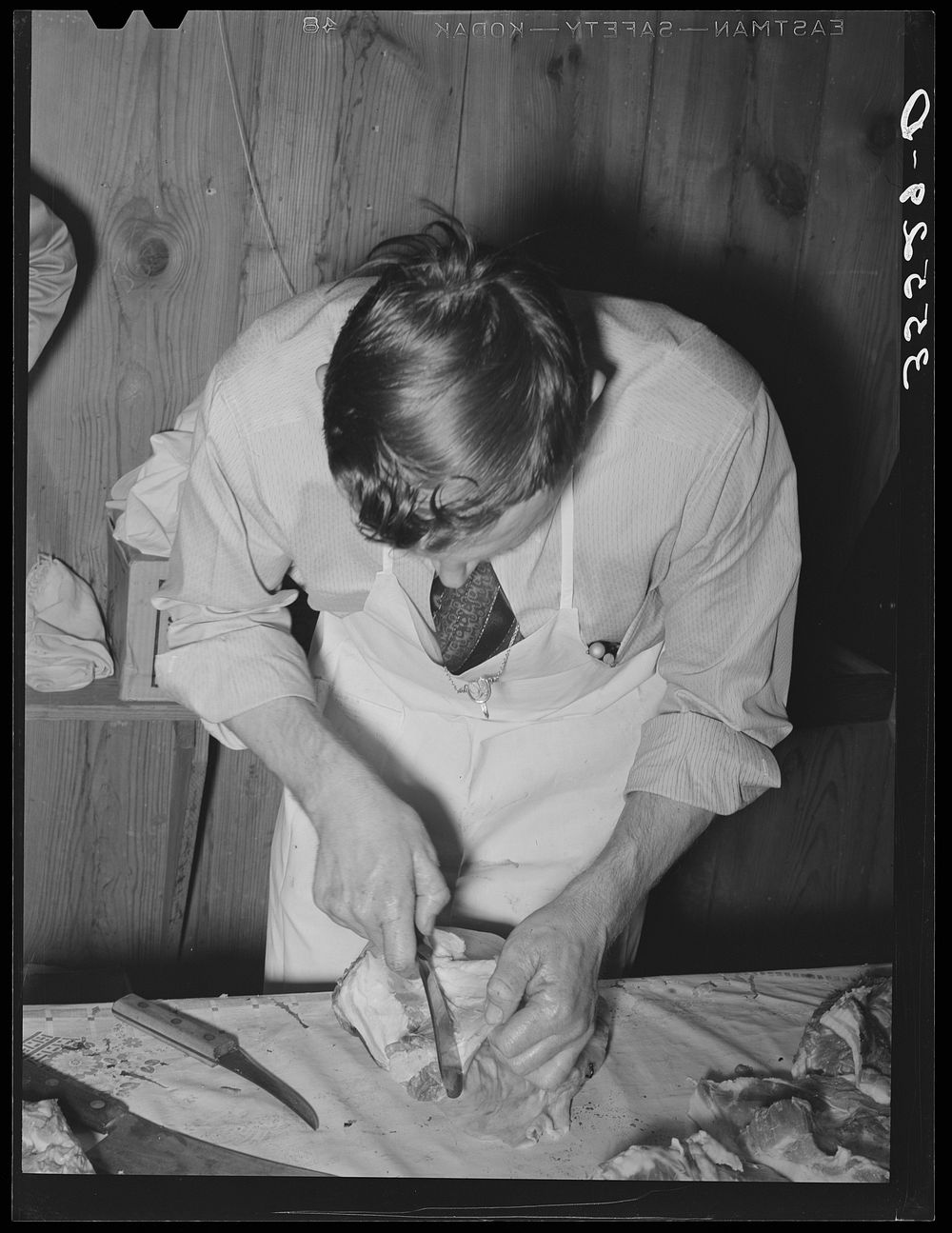 FSA (Farm Security Administration) supervisor giving a demonstration of meat cutting before a group of FSA officials and…