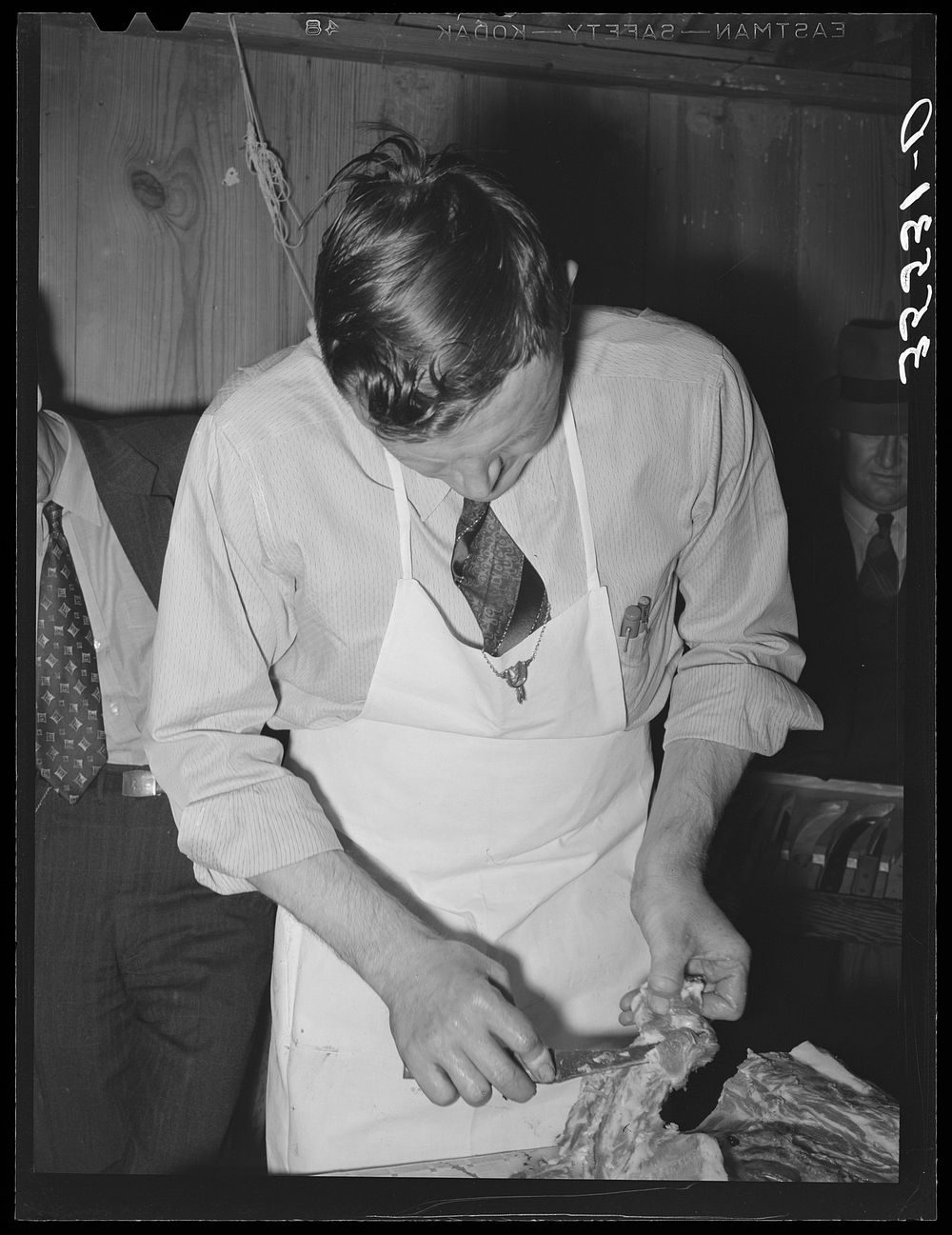 [Untitled photo, possibly related to: FSA (Farm Security Administration) supervisor sewing up a pork rolled roast during a…
