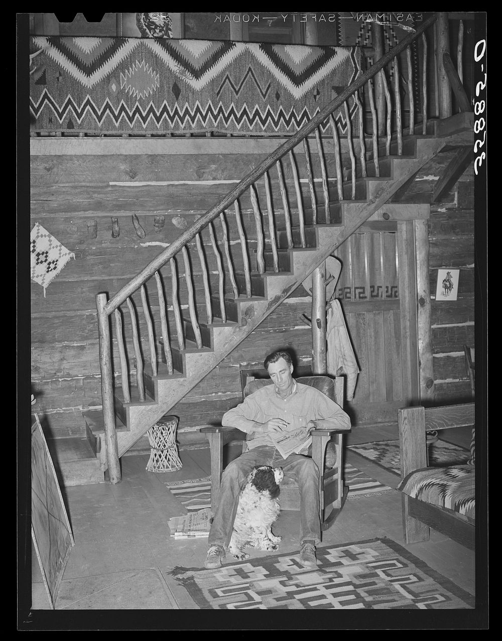 [Untitled photo, possibly related to: Manager of the Navajo Lodge working a crossword puzzle with his dog at his feet.…