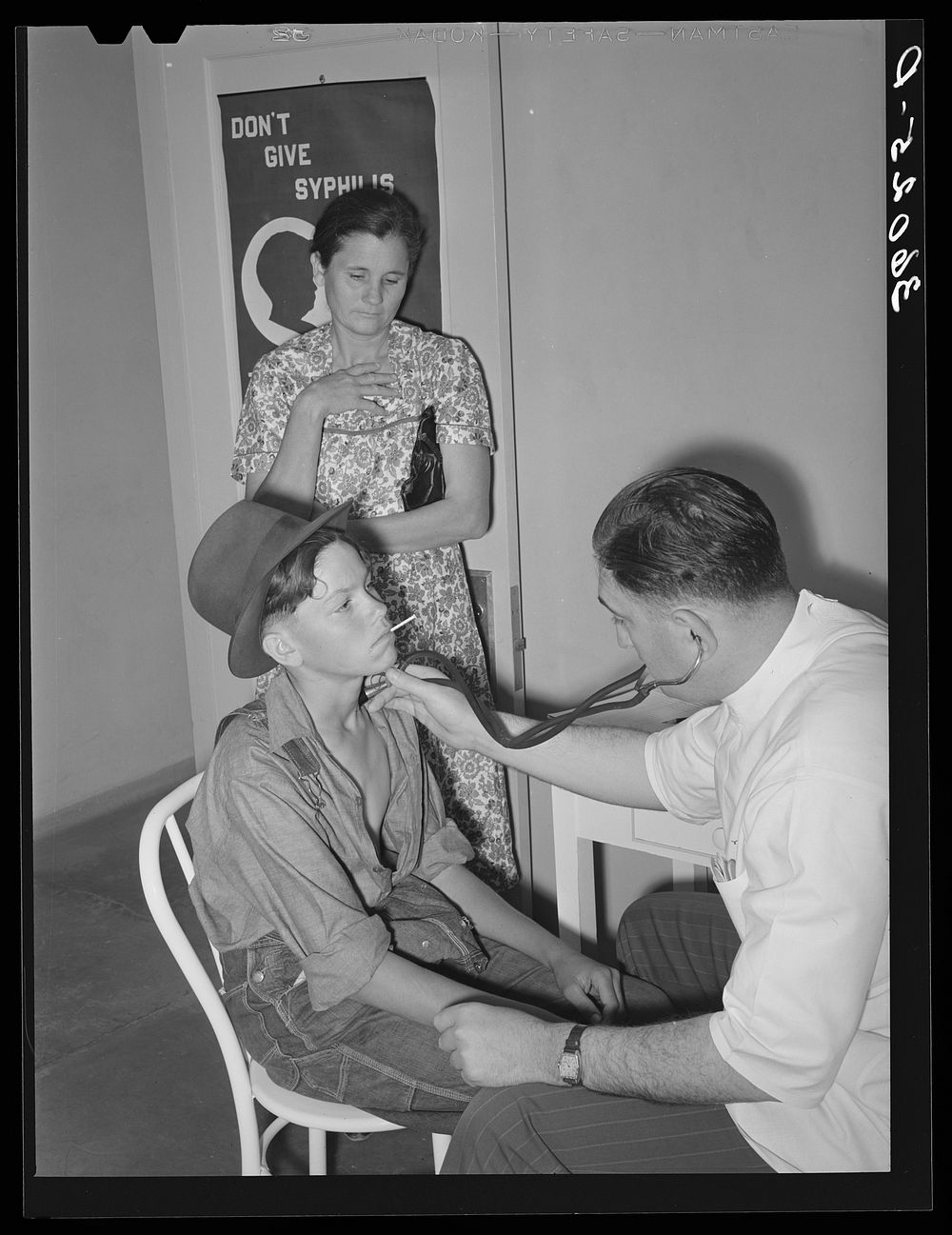 Doctor at clinic examining son of agricultural worker. Agua Fria migratory camp. Arizona by Russell Lee