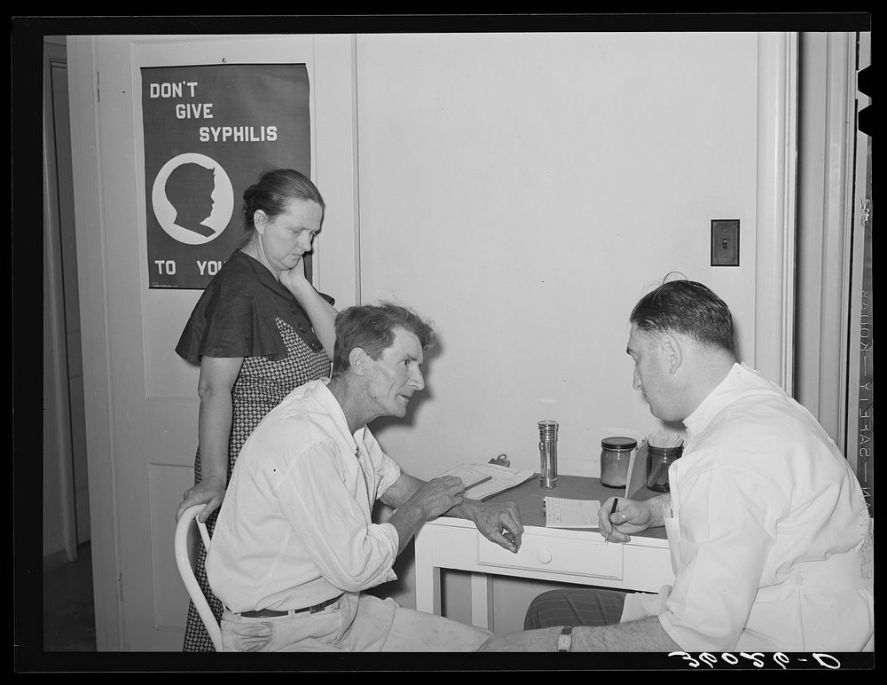 Doctor at clinic taking case history of agricultural worker. Agua Fria migratory labor camp. Arizona by Russell Lee