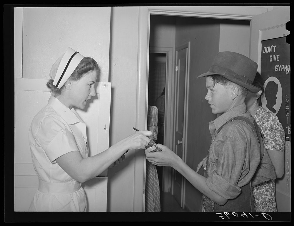 Nurse giving instructions to son of migratory laborer as to how to take medicine. Agua Fria migratory labor camp, Arizona by…