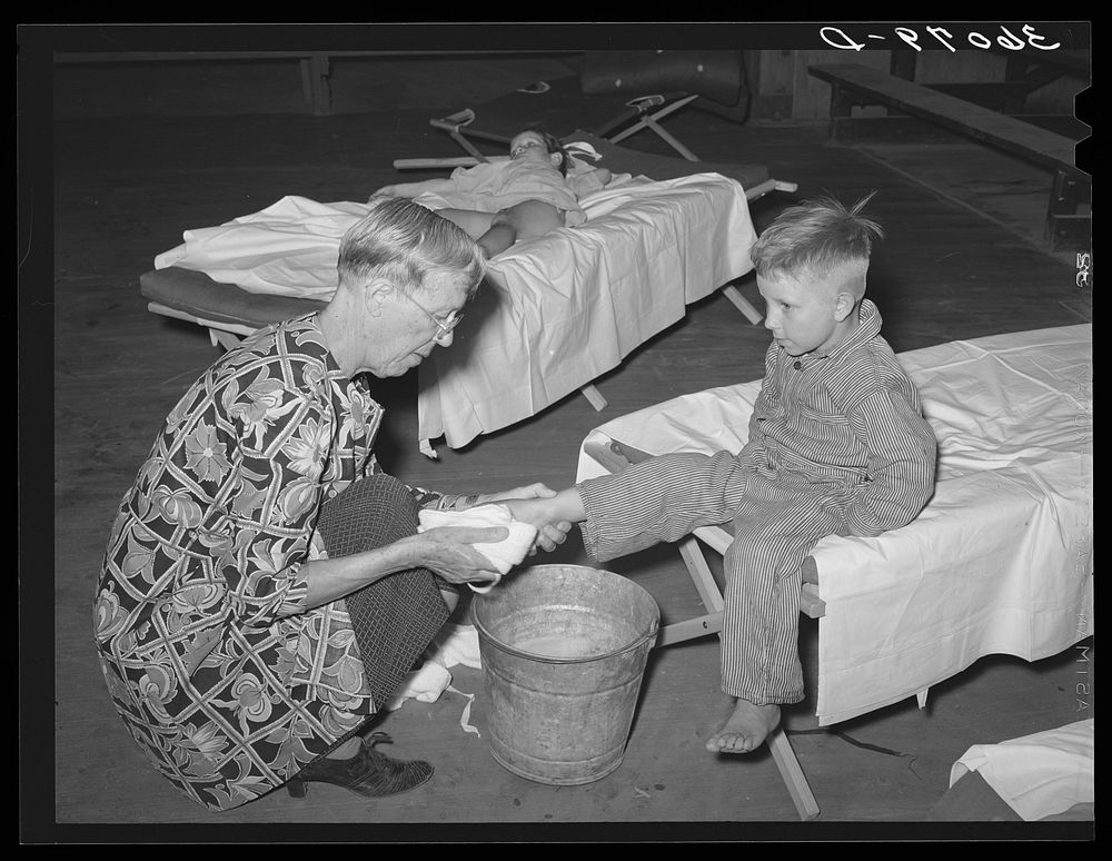 WPA (Work Projects Administration) nursery school attendent washing dirty feet of the children before they their afternoon…