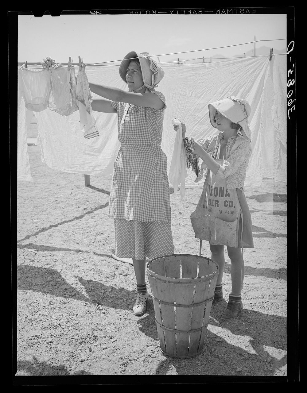 Wife of migratory agricultural laborer and daughter hanging up the wash at the Agua Fria migratory labor camp. Arizona by…