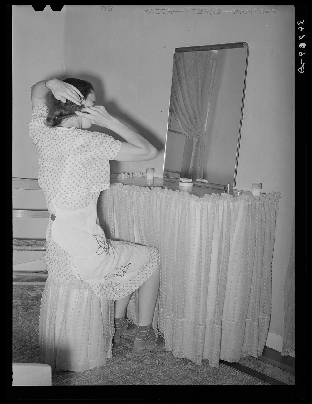 Wife of member of the Casa Grande Valley Farms sitting in front of dressing table in her home. Pinal County, Arizona by…