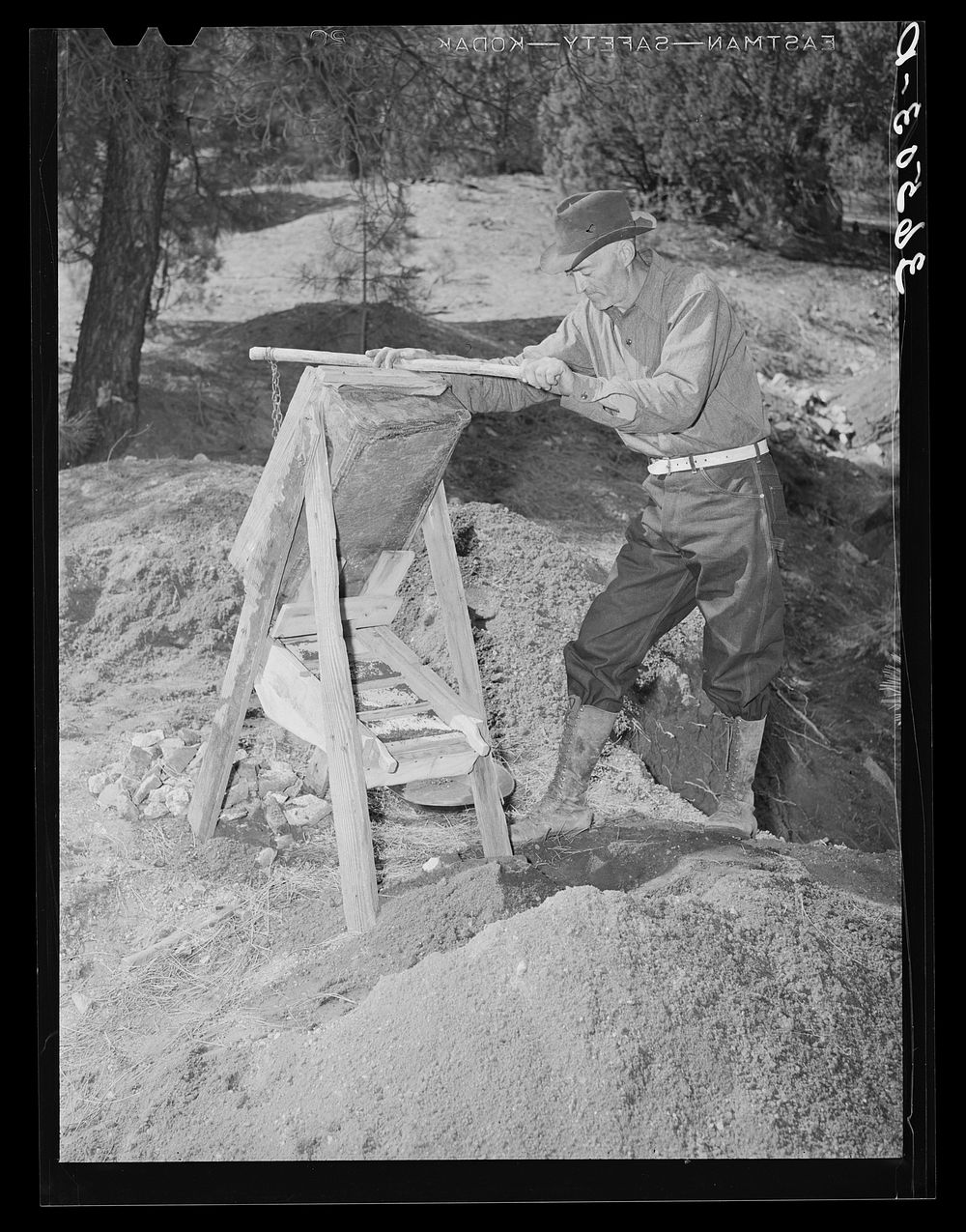 Eugene Davis, gold prospector, operating a papago (dry washer) at his diggings. Pinos Altos, New Mexico by Russell Lee