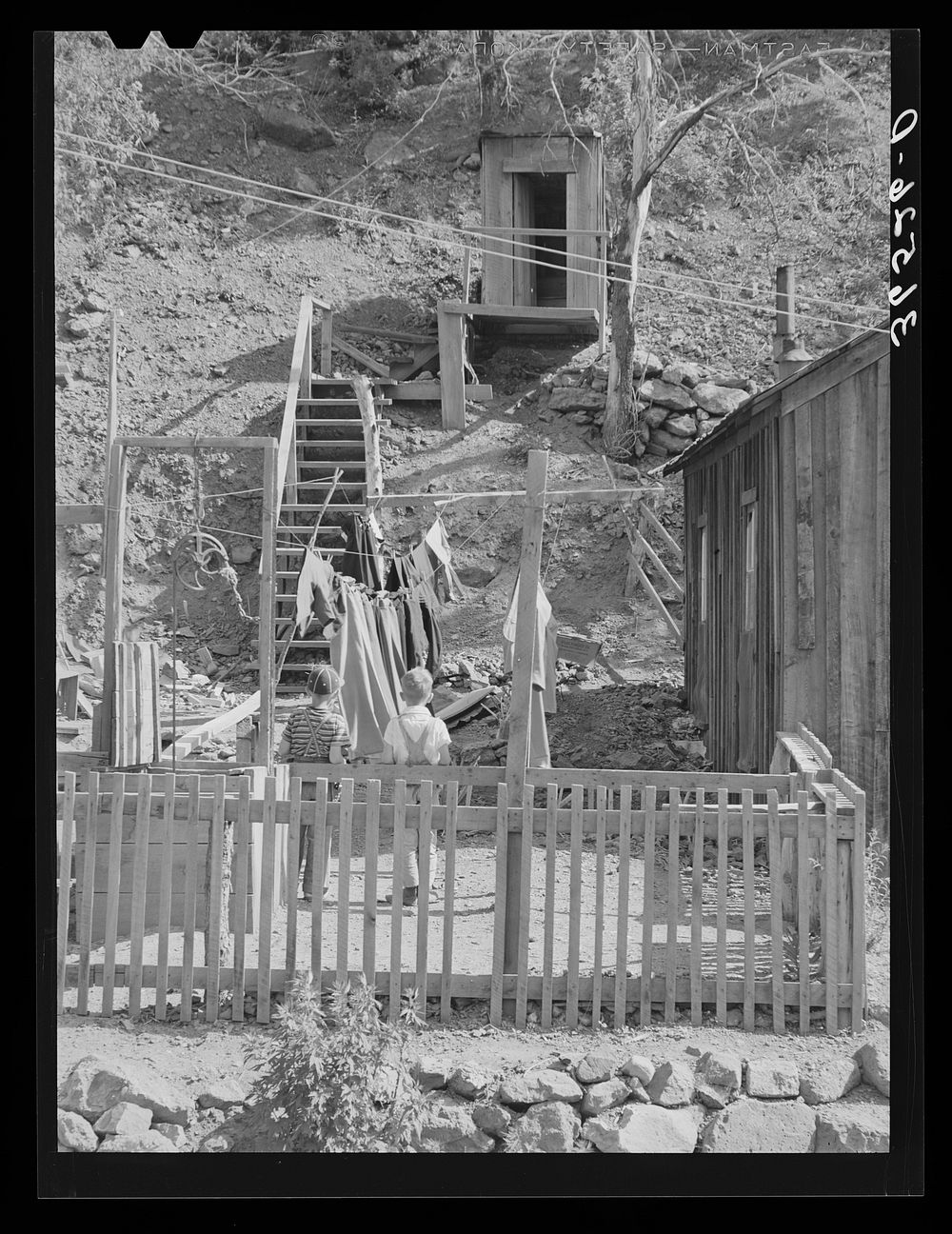 [Untitled photo, possibly related to: Backyard of house with steps leading up the hill to privy. Mogollon, New Mexico] by…