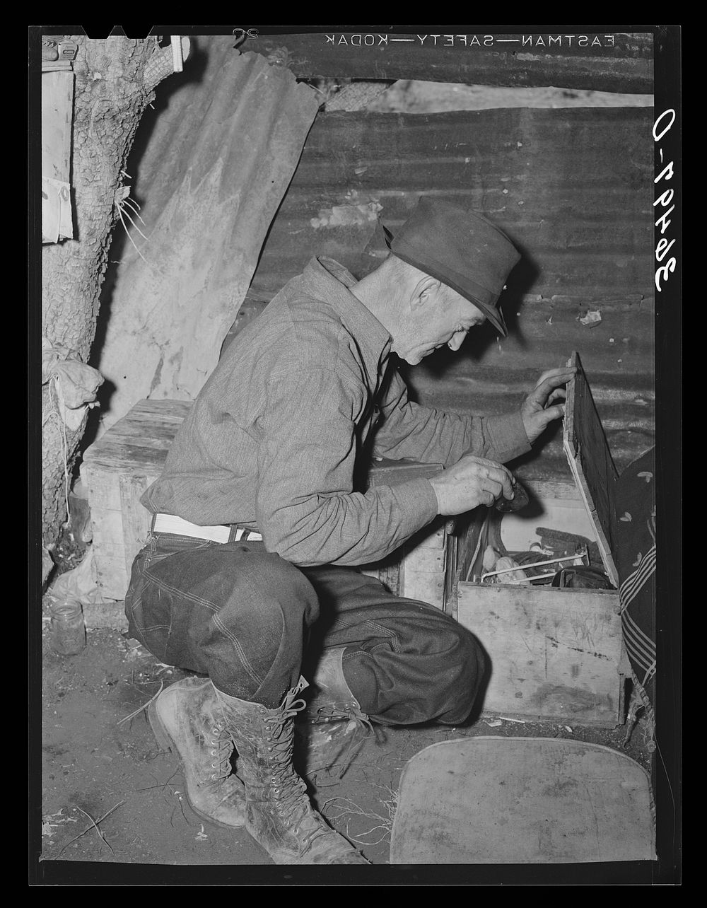 Eugene Davis, gold prospector, looking into chest where he has stored his belongings. Pinos Altos, New Mexico by Russell Lee
