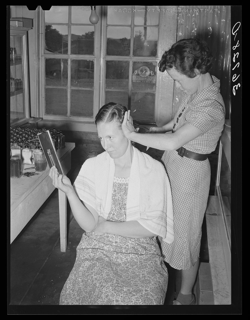 Women fix each other's hair in the absence of a beauty shop at Pie Town, New Mexico by Russell Lee