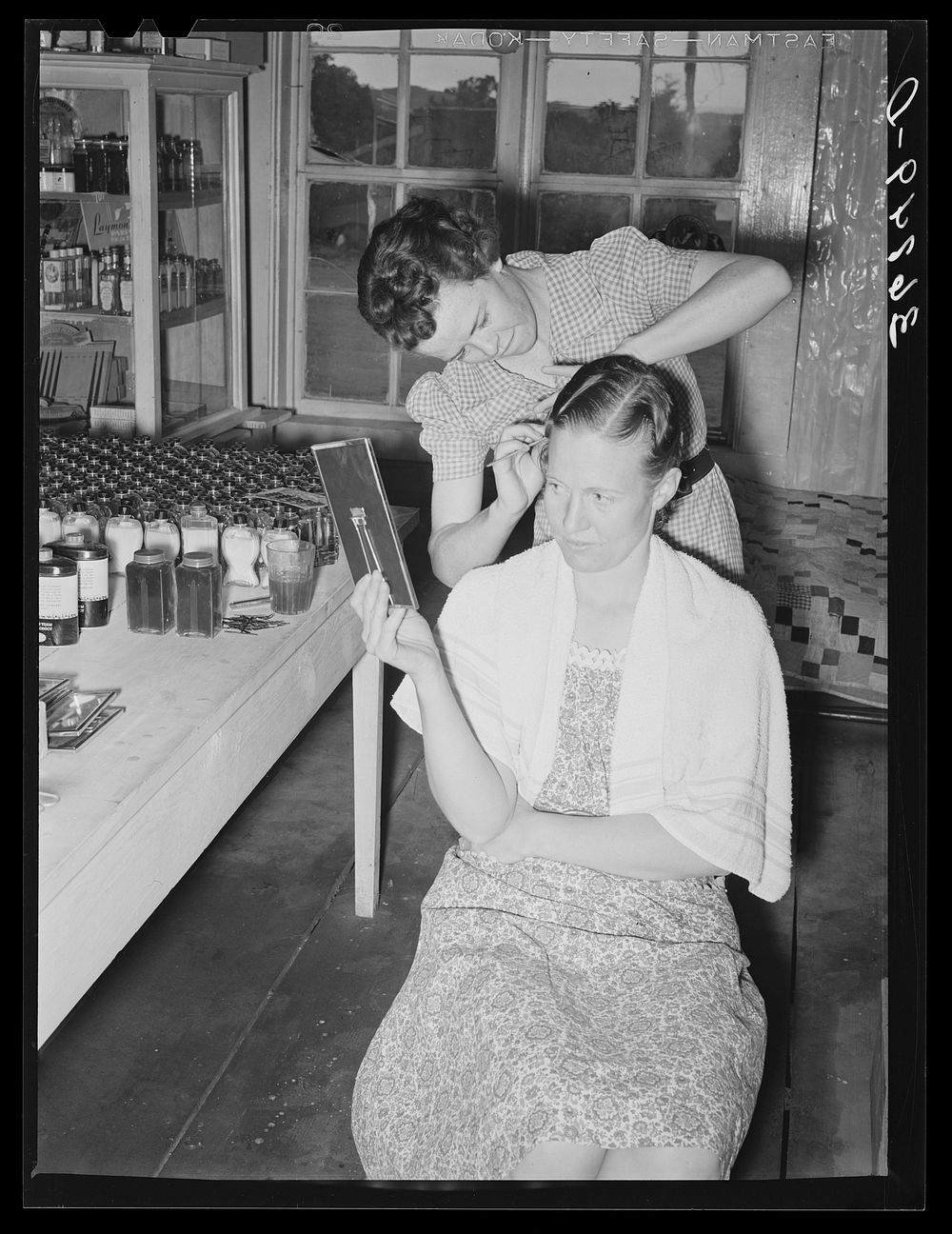 A neighbor fixes the grocery clerk's hair at Pie Town, New Mexico by Russell Lee