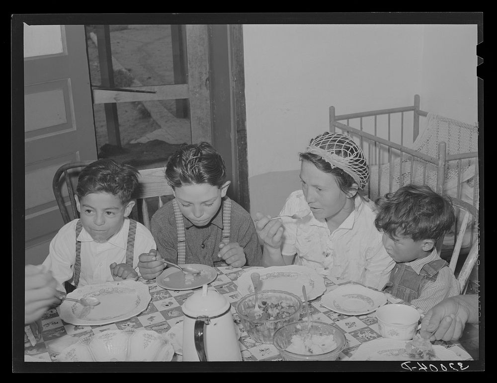Spanish-American family eating dinner. Chamisal, New Mexico by Russell Lee