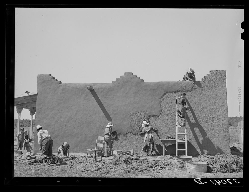 [Untitled photo, possibly related to: Spanish-American women replastering an adobe house. This is done once a year.…
