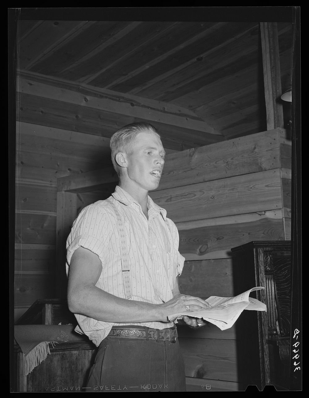 Young farm boy leading community sing. Pie Town, New Mexico by Russell Lee