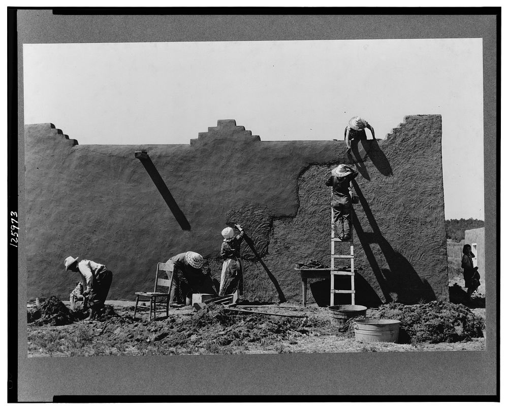 Spanish-American women replastering an adobe house. This is done once a year. Chamisal, New Mexico by Russell Lee