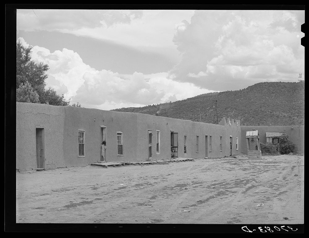 Row of adobe dwellings in Costilla, New Mexico. Well in square supplies several families with water by Russell Lee