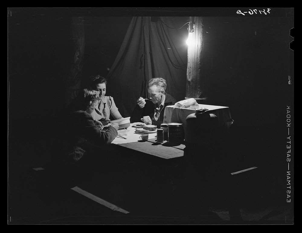 Carpenter, his wife and daughter eating supper in front of their tent-home. Mission Valley, California, about three miles…
