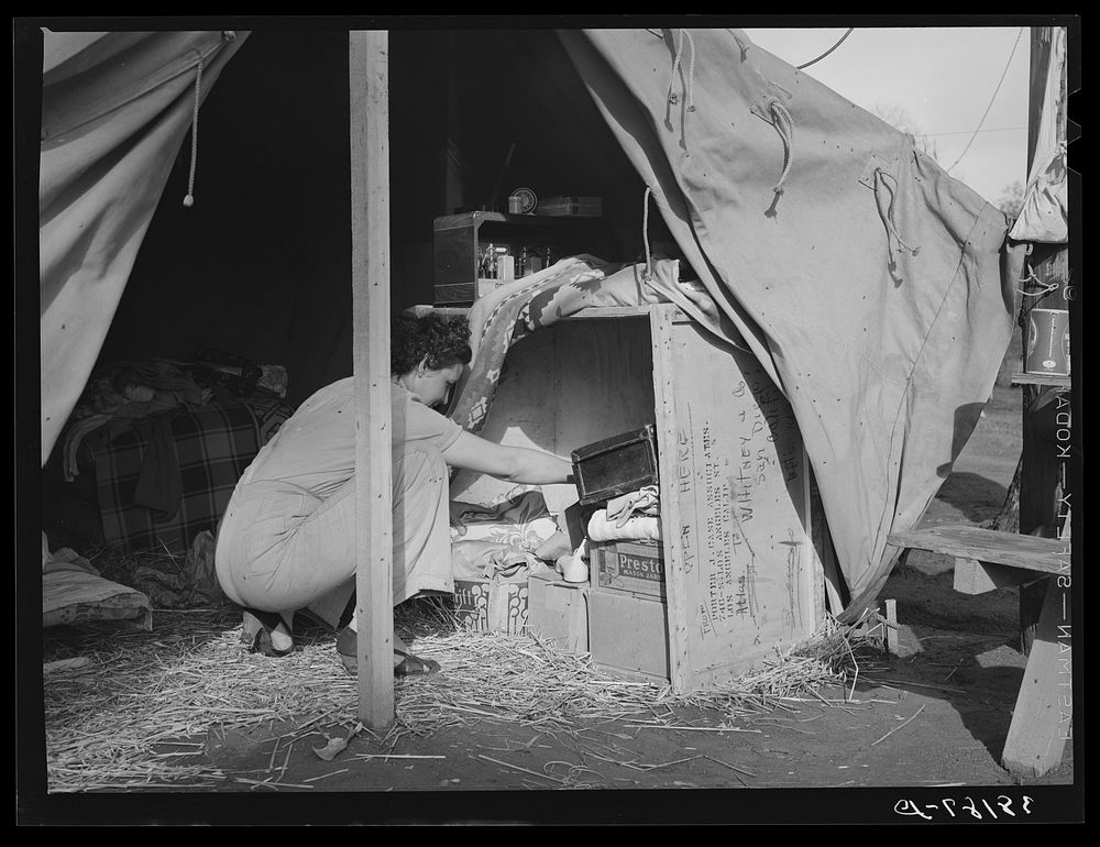 Carpenter's wife taking things out of improvised closet in her tent-home. Mission Valley, California, about three miles from…