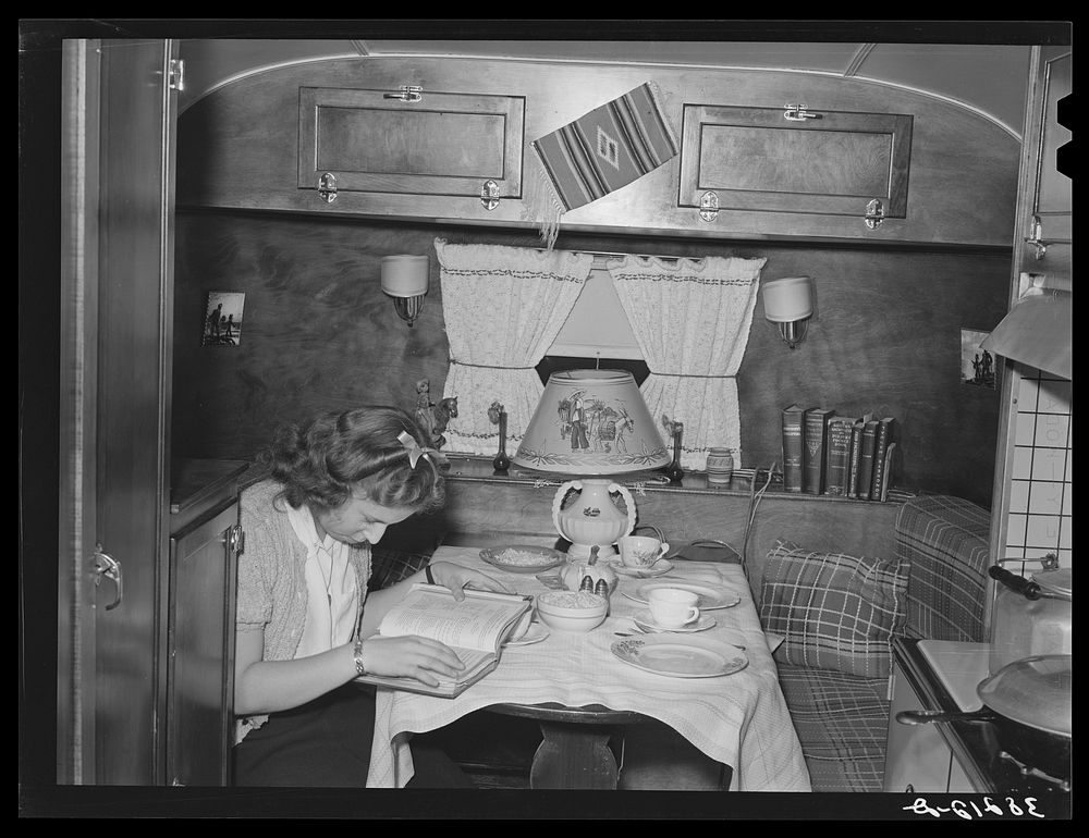 End of trailer with high school girl studying as she waits for supper time. San Diego, California. Trailer courts dot the…