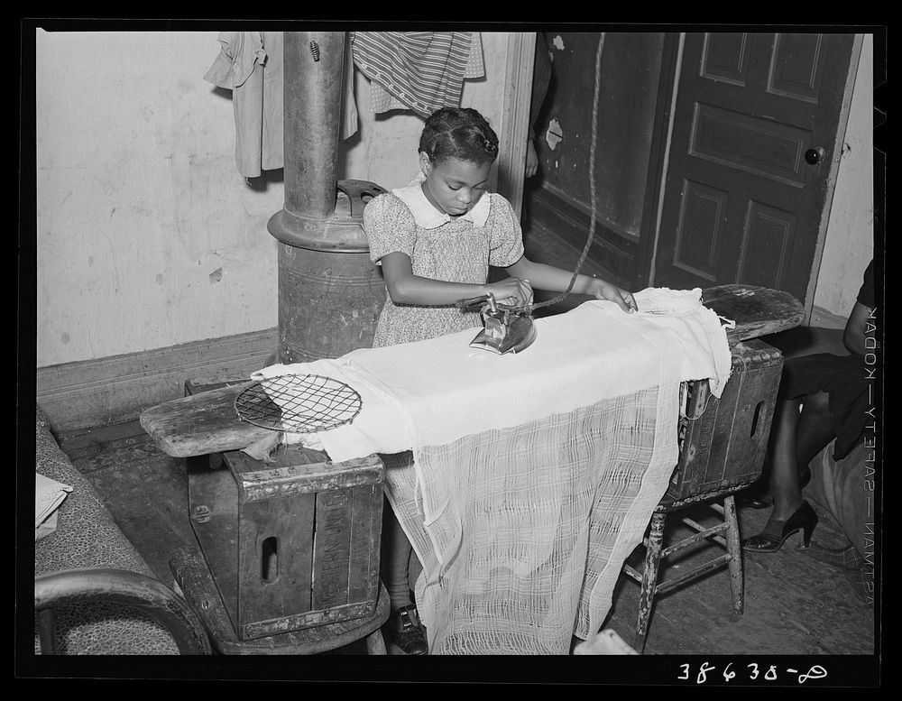 Little girl ironing. Family is on relief. Chicago, Illinois by Russell Lee