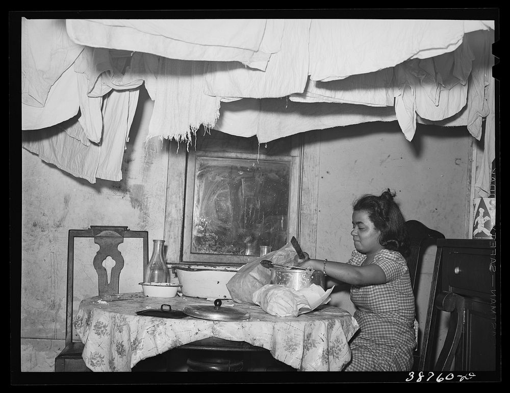 Preparing the evening meal. Notice the laundry hanging near the ceiling. Chicago, Illinois by Russell Lee