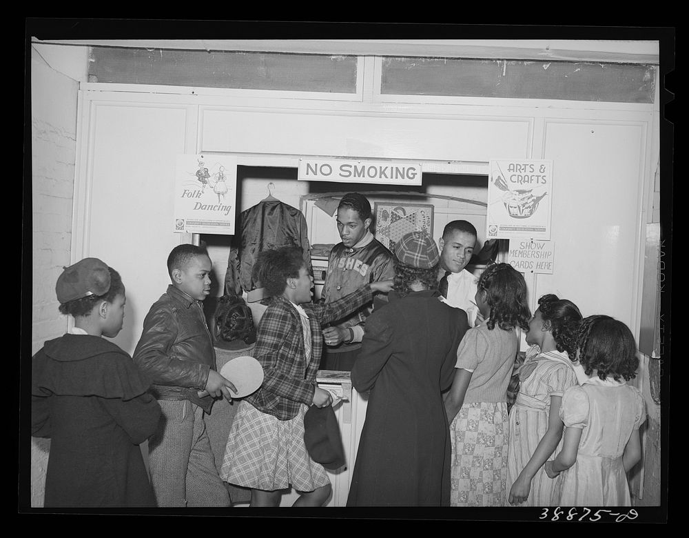 Boys and girls presenting membership cards at recreational booth in basement of the Good Shepherd Community Center. Chicago…