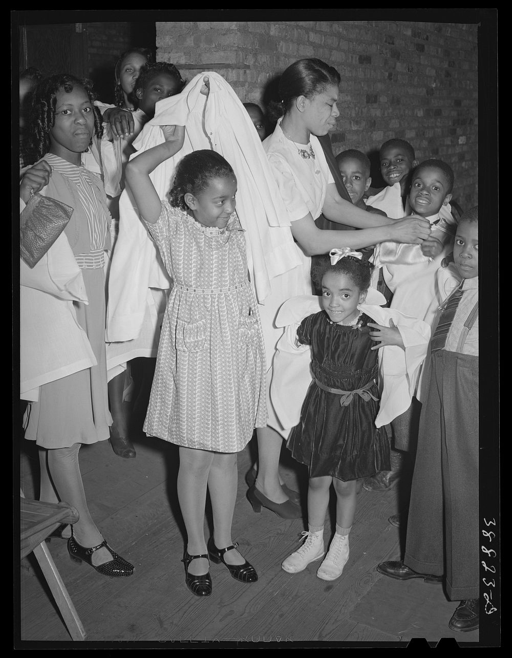 Children putting on choir robes. Pentecostal church. Chicago, Illinois by Russell Lee