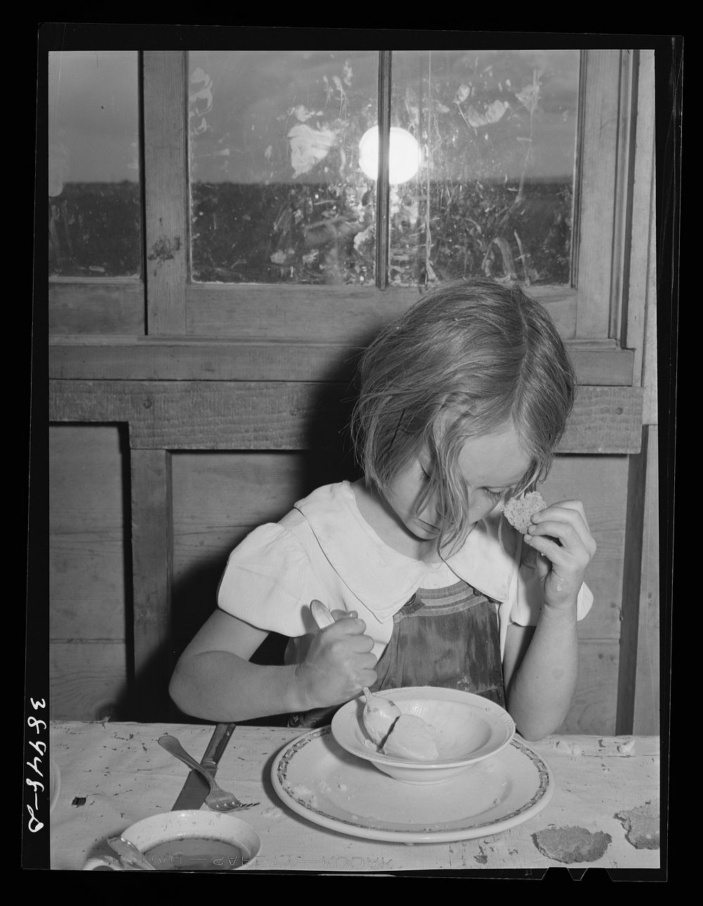 Daughter of Ray Halstead eating ice cream made in her mother's electric refrigerator. He is an (Farm Security…