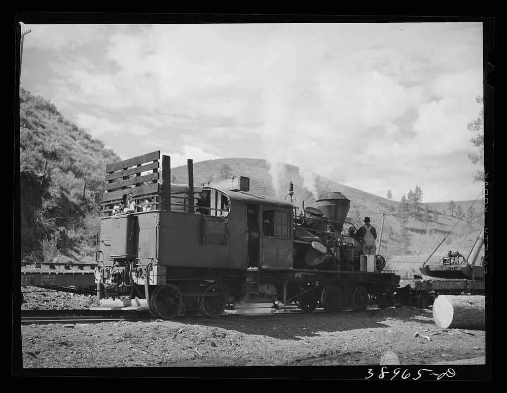 Locomotive of logging train. Baker County, Oregon. There has been a tendency to change from the logging train to trucks to…