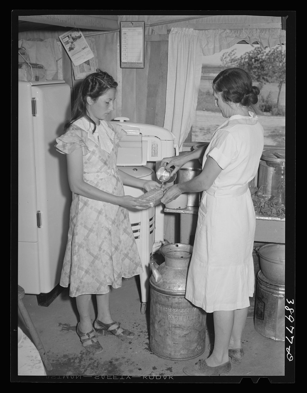 Mrs. Browning and her daughter fill ice trays for electrical refrigeration. They are FSA (Farm Security Administration)…