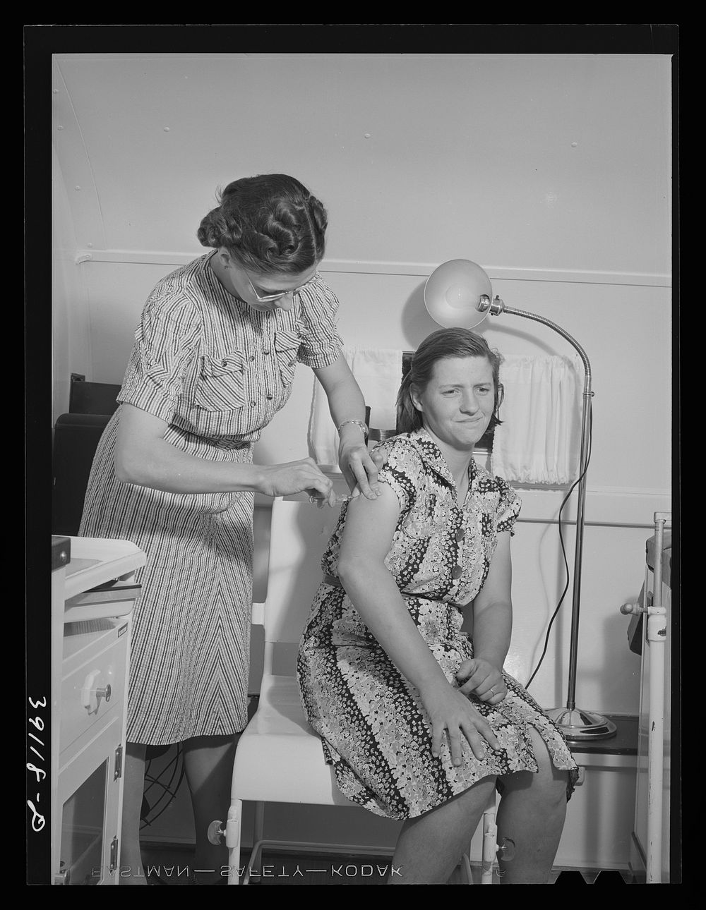 Nurse administers hypodermic to wife of farm worker who lives at the FSA (Farm Security Administration) migratory labor camp…
