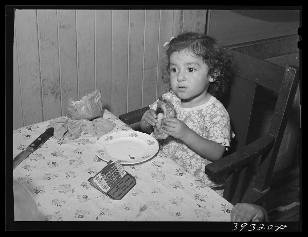 Little Mexican girl eating enchilada for lunch. San Diego, California by Russell Lee