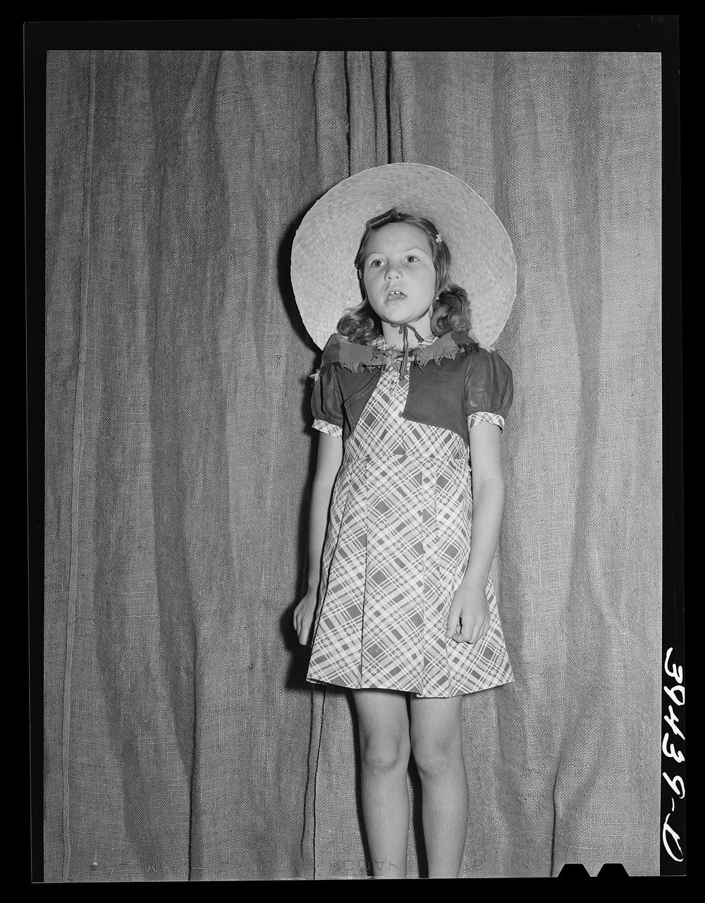 Daughter of migratory farm worker in program at the end of school term. FSA (Farm Security Administration) labor camp.…