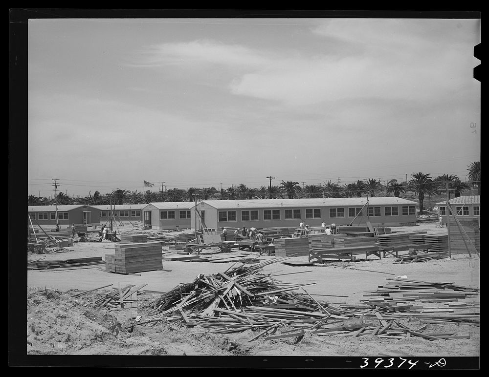 Working on jigs, with dormitories in the background at the FSA (Farm Security Administration trailer camp for defense…