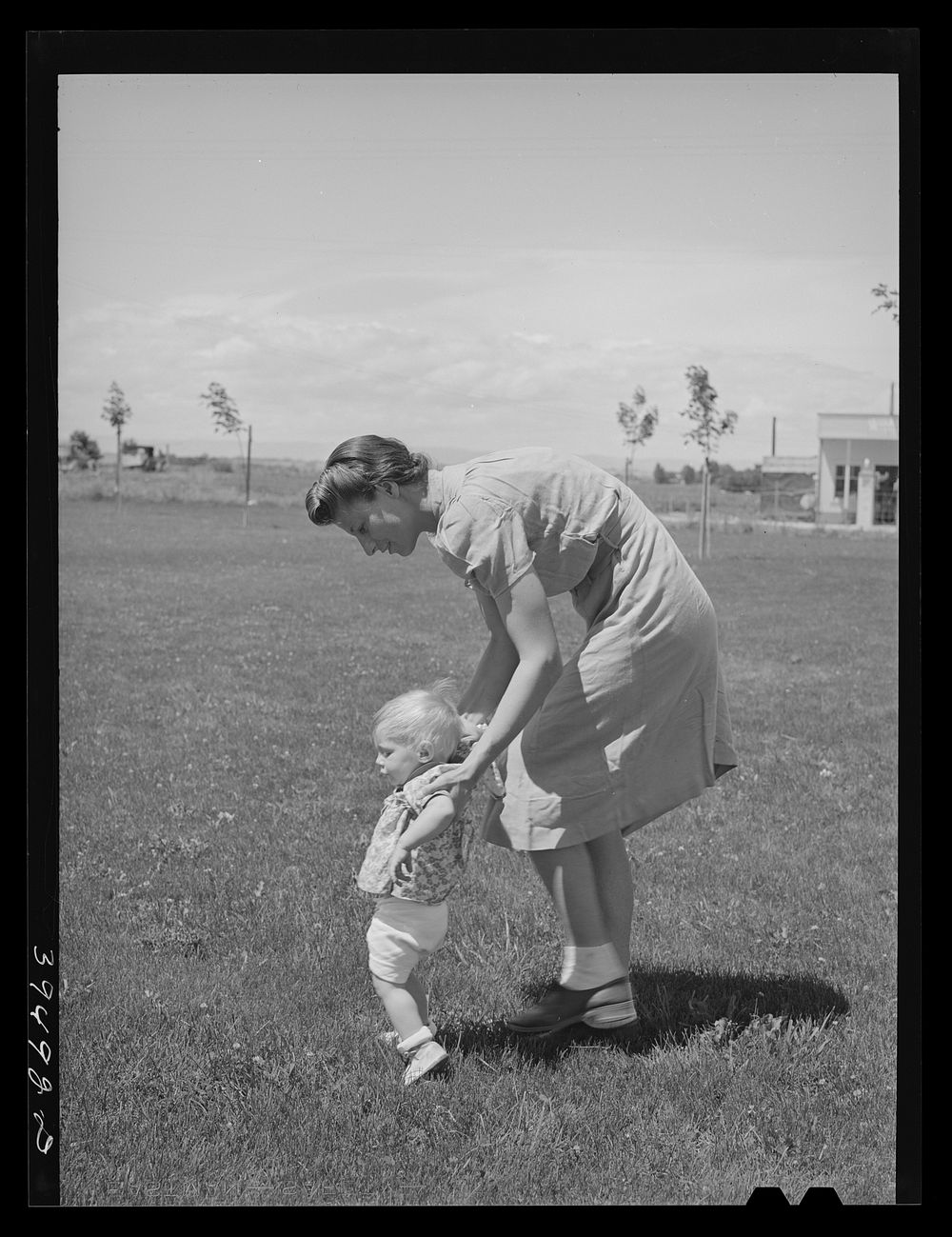 [Untitled photo, possibly related to: Farm worker's wife teaches her baby girl to walk a the FSA (Farm Security…