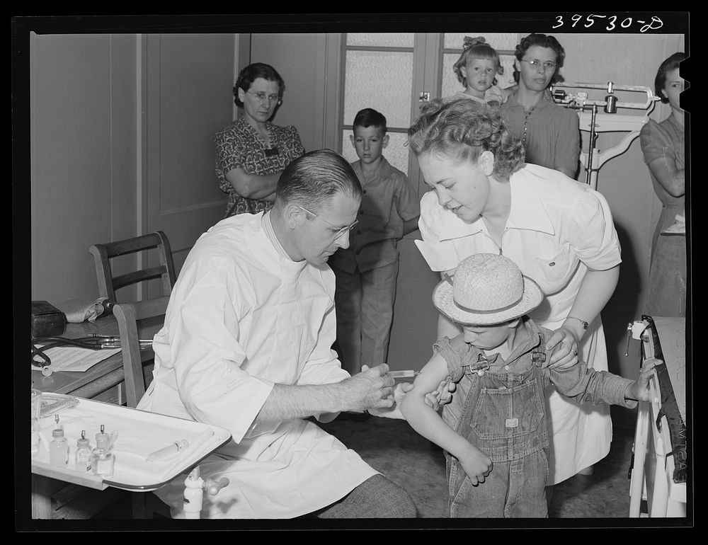 A little boy gets a shot (tick fever serum) at the clinic at the FSA (Farm Security Administration) farm labor camp.…