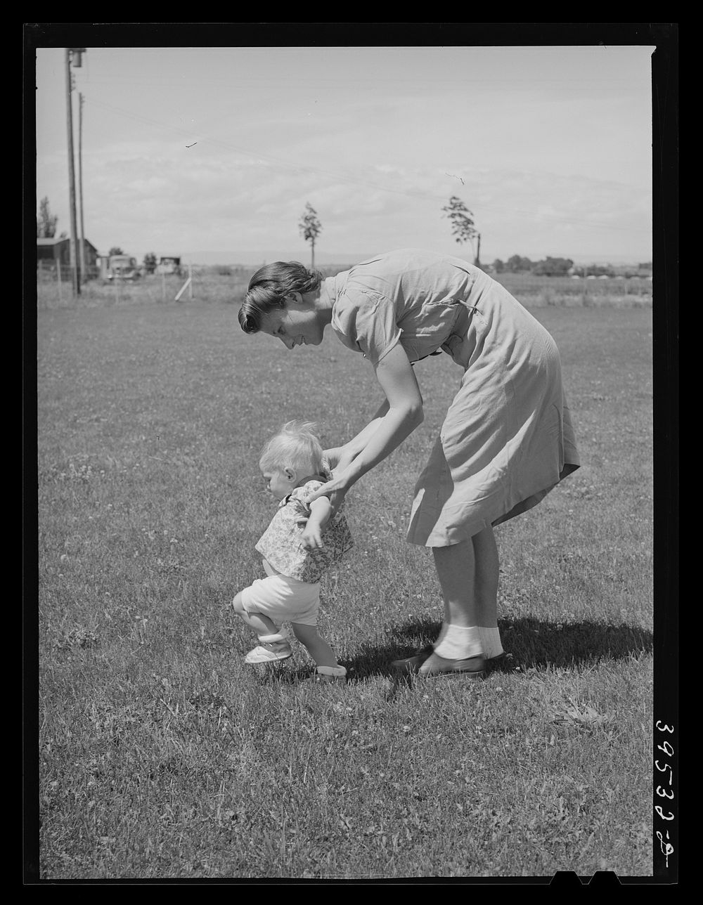 Farm worker's wife teaches her baby girl to walk at the FSA (Farm Security Administration) labor camp. Caldwell, Idaho by…