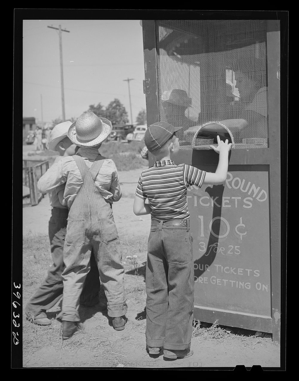 Farm boys buy tickets for ride at the carnival on the Fourth of July. Vale, Oregon by Russell Lee