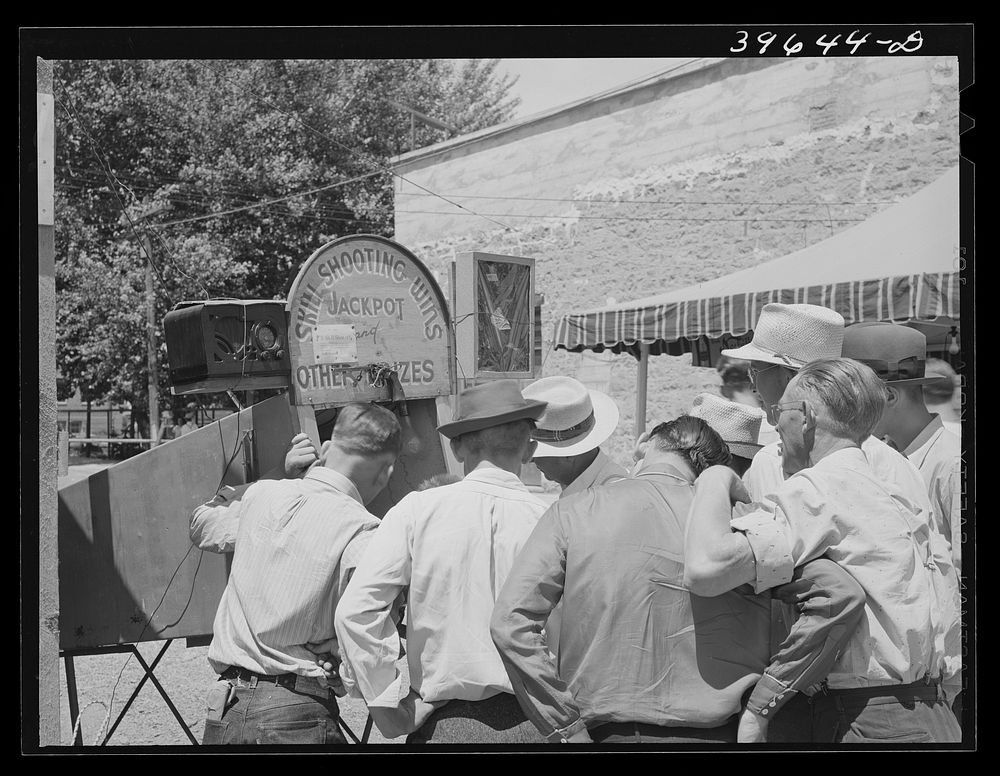 [Untitled photo, possibly related to: Men gathered around one of the carnival attractions which was in Vale, Oregon, for the…