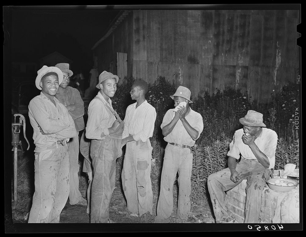 Group of migratory agricultural workers at grading station at Belcross, North Carolina, stop to wash and have their supper.…