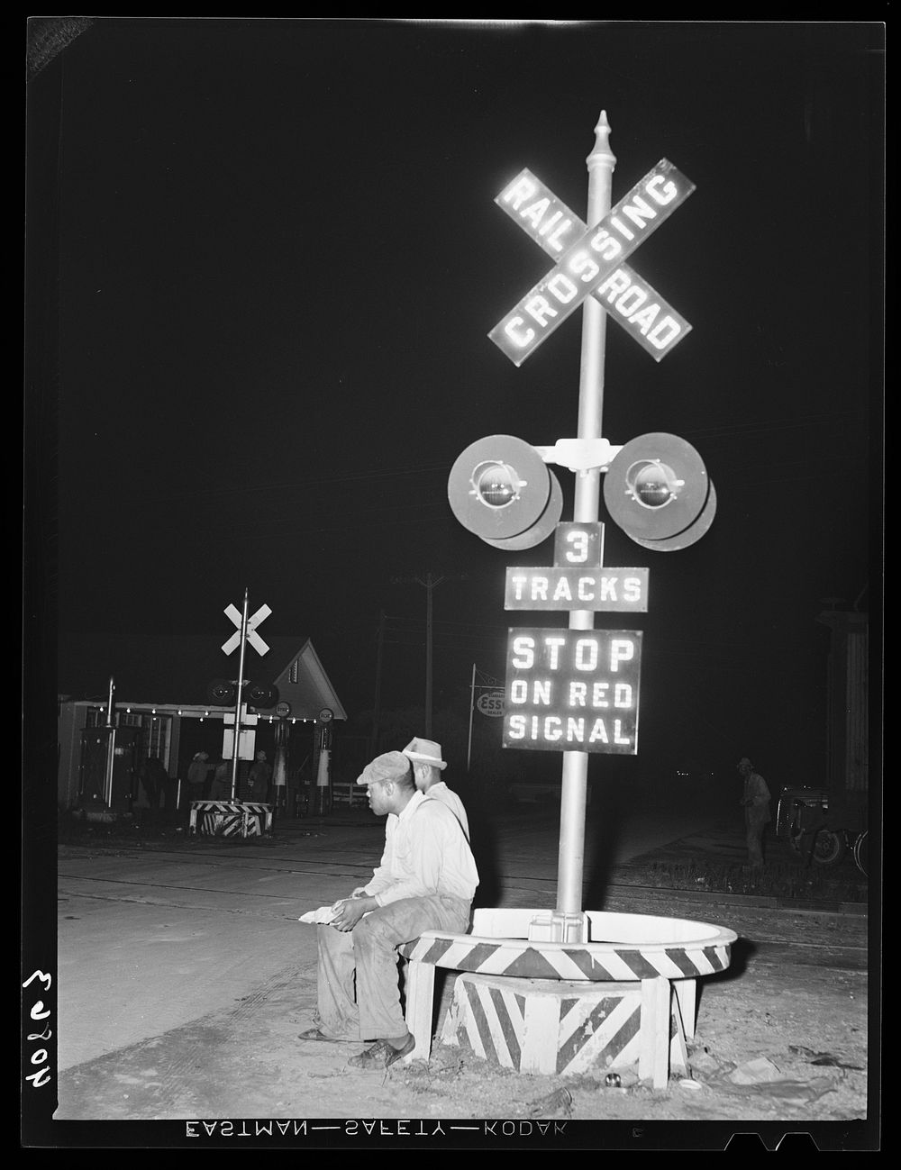 Migratory agricultural workers having supper at the railroad crossing at Camden, North Carolina. Sourced from the Library of…