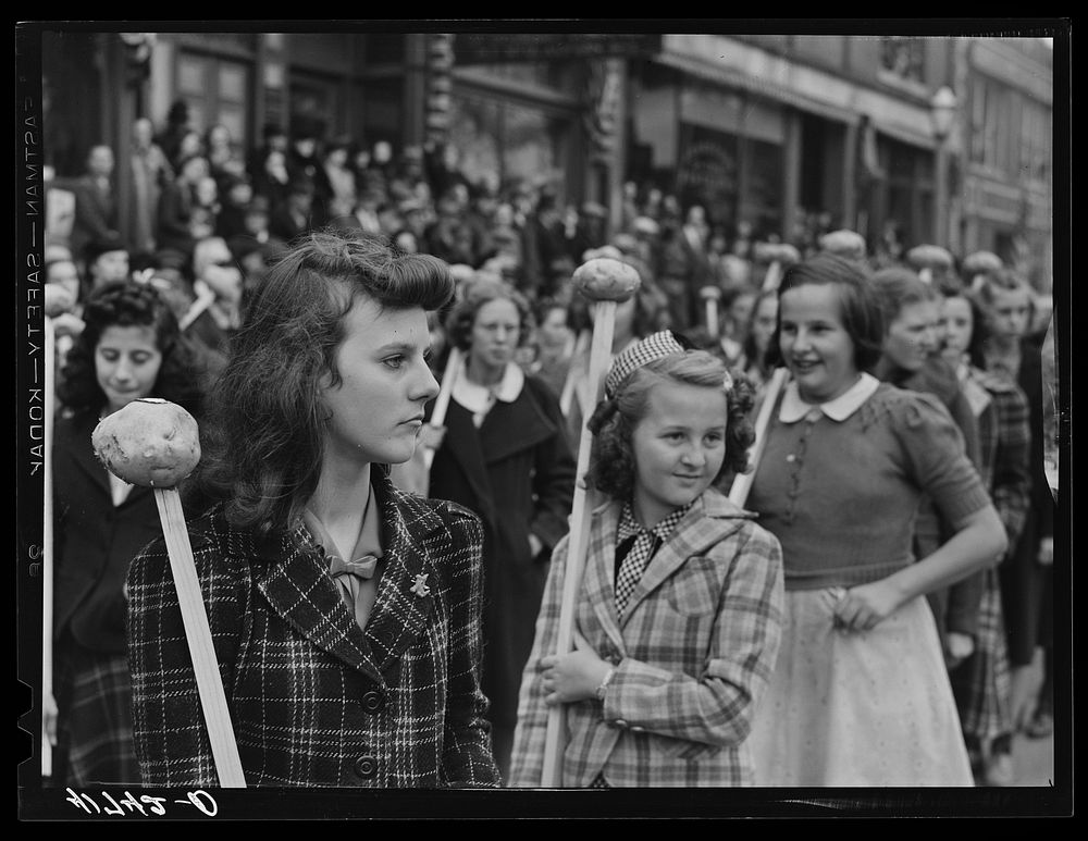 Schoolgirls carrying Aroostook potatoes on sticks as part of the parade on the day of the barrel rolling contest in Presque…