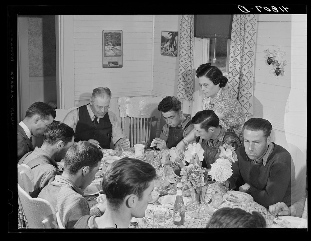Lunch being served at one of the farms of the Woodman Potato Company. At the head of the table is Mr. Woodman. Only the…