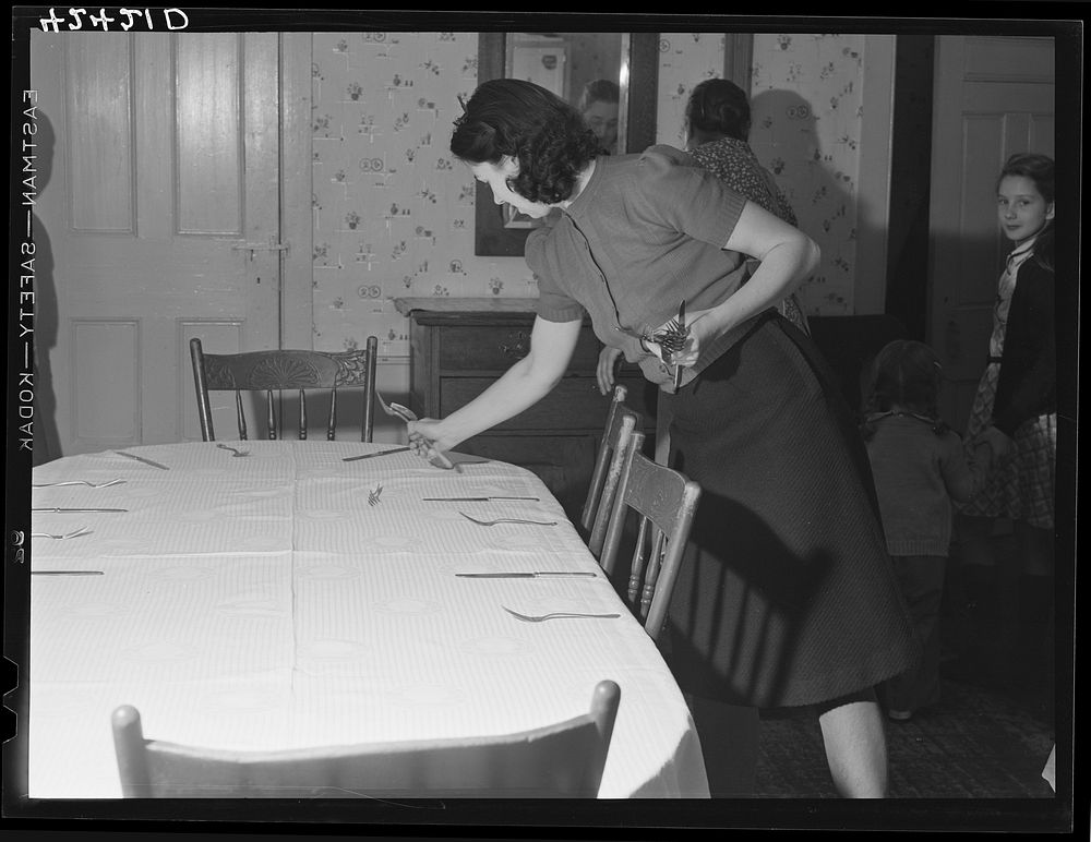 One of the daughters of Mr. T.L. Crouch setting the table for the family on Thanksgiving Day. Sourced from the Library of…