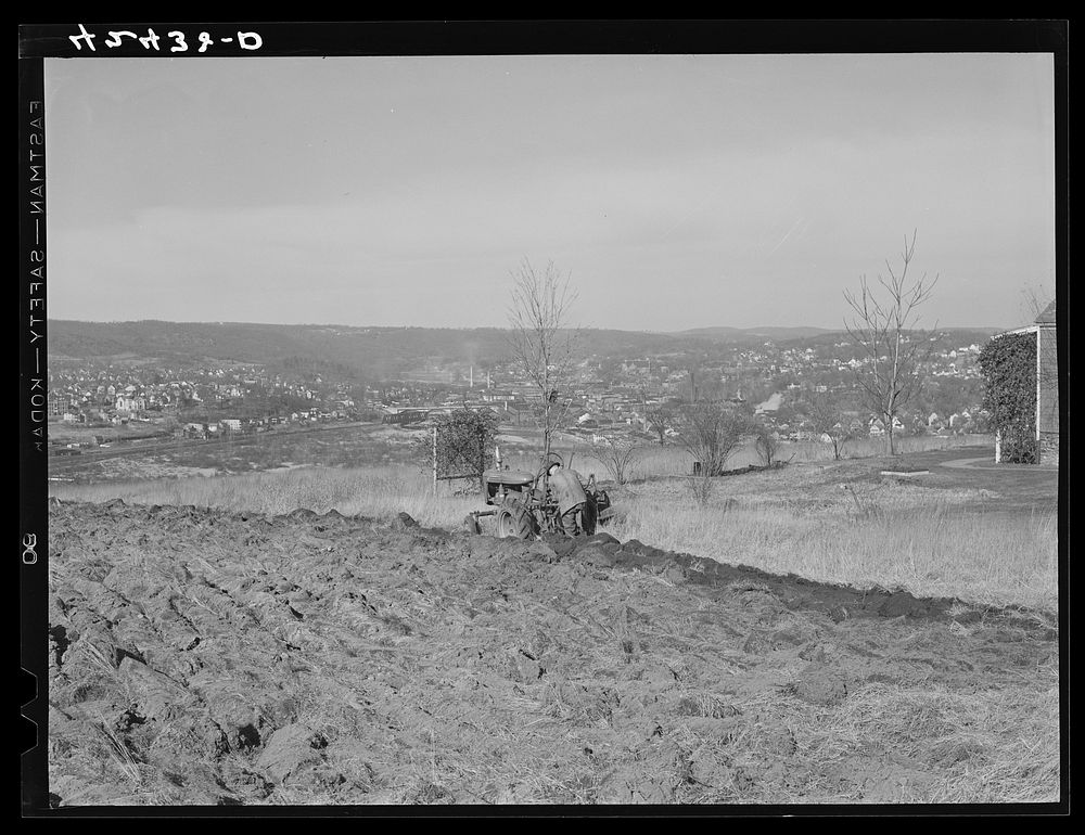 [Untitled photo, possibly related to: Farmer ploughing his field on a hillside opposite the industrial valley including the…