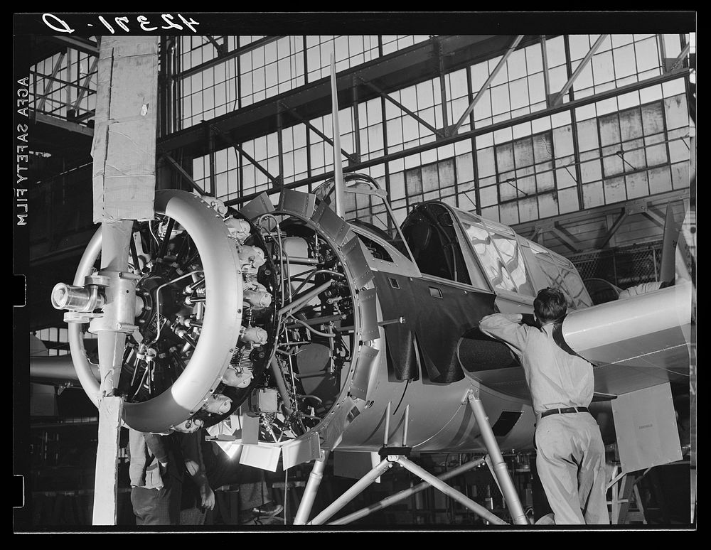 Workmen on the final assembly of a plane at the Vought Sikorsky Aircraft Corporation. Stratford, Connecticut. Sourced from…