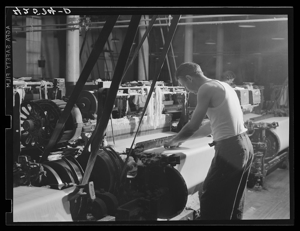 At a loom in the Denomah Mills, Taftville, Connecticut. Makers of rayon and cotton cloths. Sourced from the Library of…