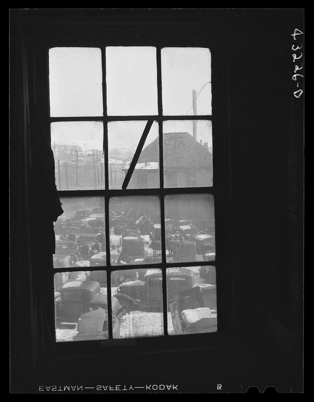 Auto graveyard seen thru a window of the abandoned Olive Stove Works, Rochester, Pennsylvania. Sourced from the Library of…