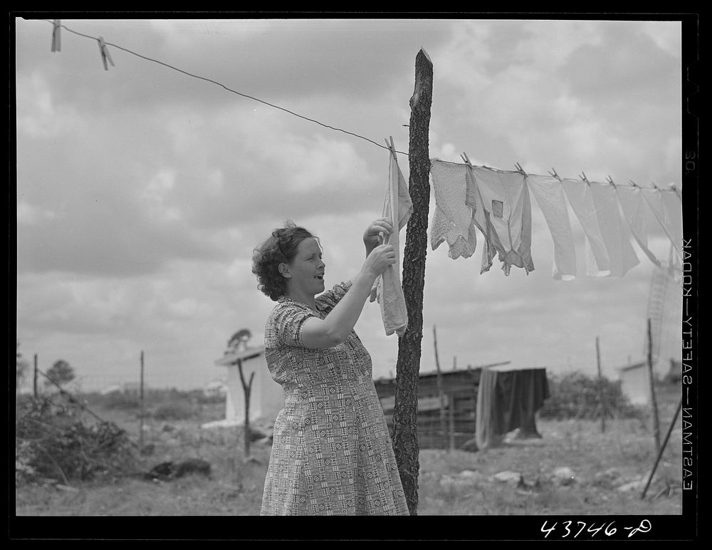 Mrs. Agnes Usher hanging clothes at her new prefabricated house at Hazlehurst Farms Inc. She had gone to Hinesville with her…